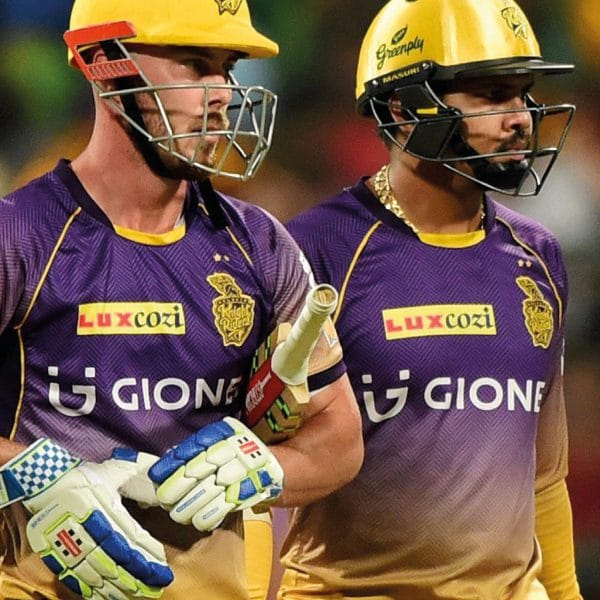 A photograph of two Kolkata Knight Rider players in helmet carrying a cricket bat