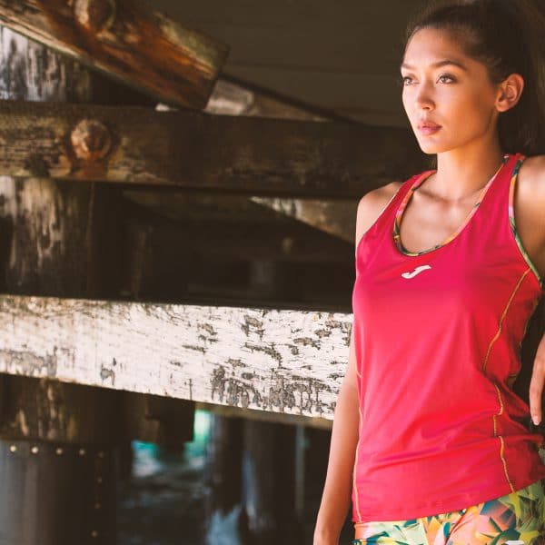 Female runner wearing a pink vest resting under a pier