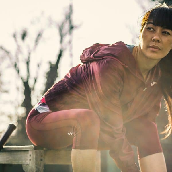 Female runner sitting down in a red Joma tracksuit