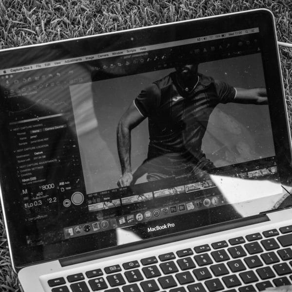 A photograph of a MacBook showing an image on screen of a football player