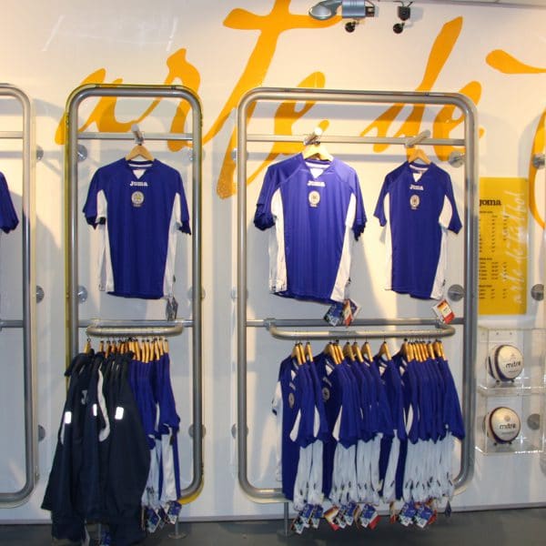 An image showing Joma football shirts hanging in a retail display